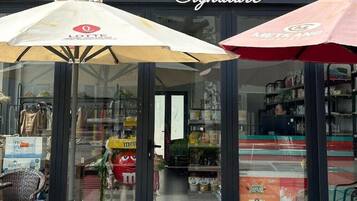 A storefront with a sign reading 'Taka Signature' and two umbrellas in front.