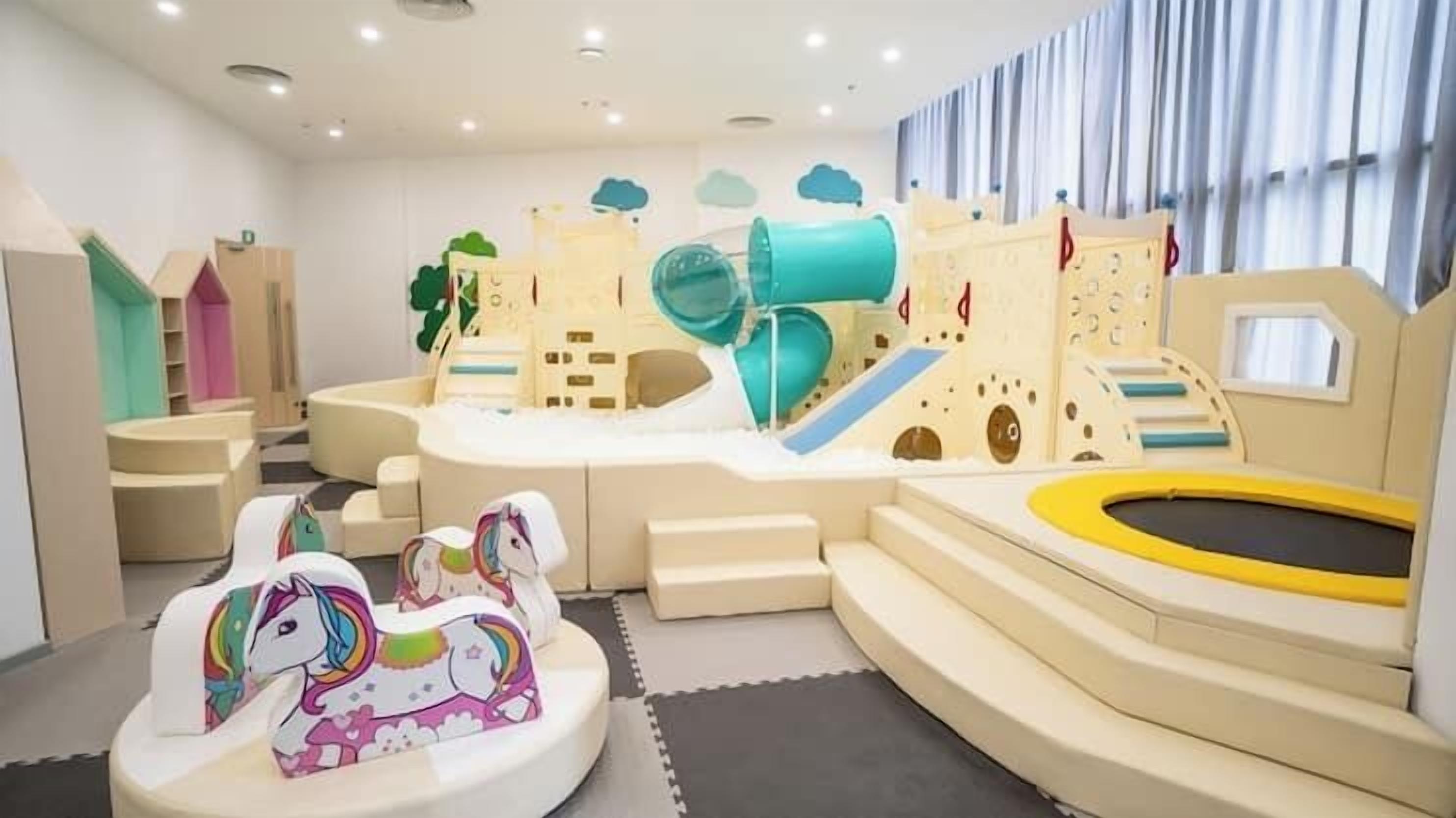 A play area with a slide, a small castle, and a trampoline.
