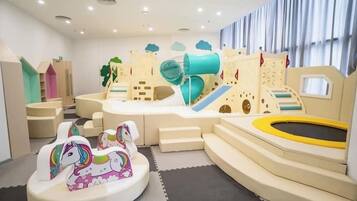 A play area with a slide, a small castle, and a trampoline.