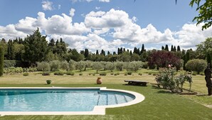 A swimming pool surrounded by well-maintained grass and trees, with a clear sky above.