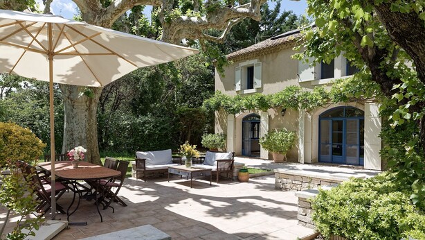 A patio with outdoor furniture, a table, and an umbrella.