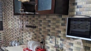 A kitchen with a tiled backsplash, stainless steel sink, and a dish drying rack. - APPARTEMENTS 2 PIECES BELLE RIVE  (Abidjan)