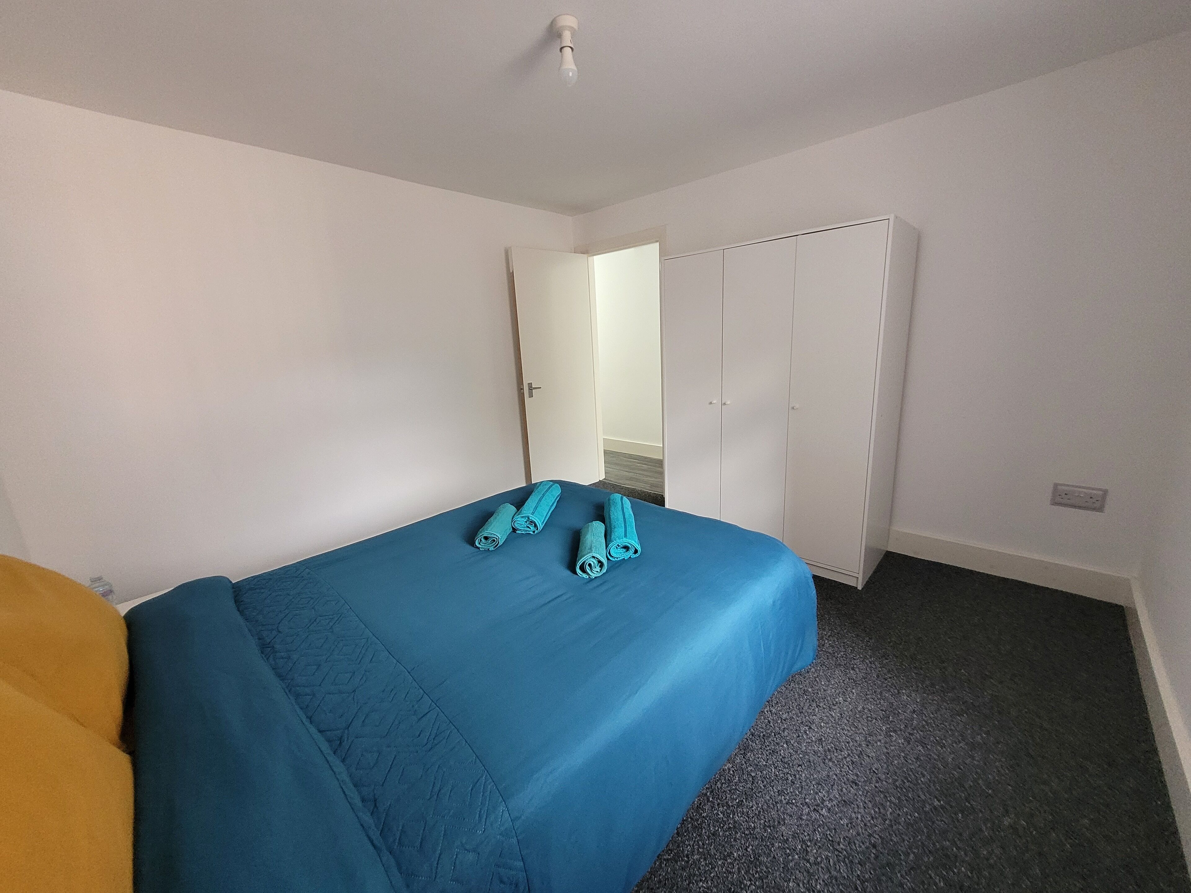 Un dormitorio con una cama individual, un armario y una puerta que da a otra habitación.
