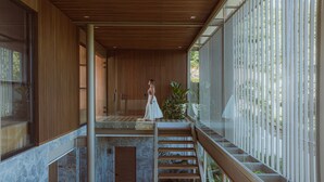 Un intérieur moderne avec un mur à lattes de bois, un escalier en verre et une vue sur la verdure à l’extérieur.