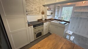 Una cocina compacta con armarios blancos, un horno empotrado y una encimera de madera.