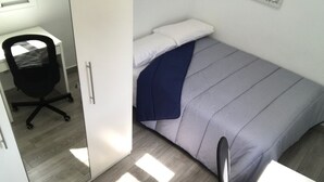 Habitación compacta con cama, escritorio y silla.