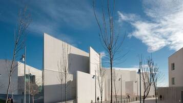 A modern building with a flat roof and large windows, surrounded by a grassy area and bare trees.