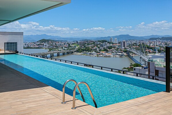 A rooftop infinity pool with a view of a cityscape and mountains.