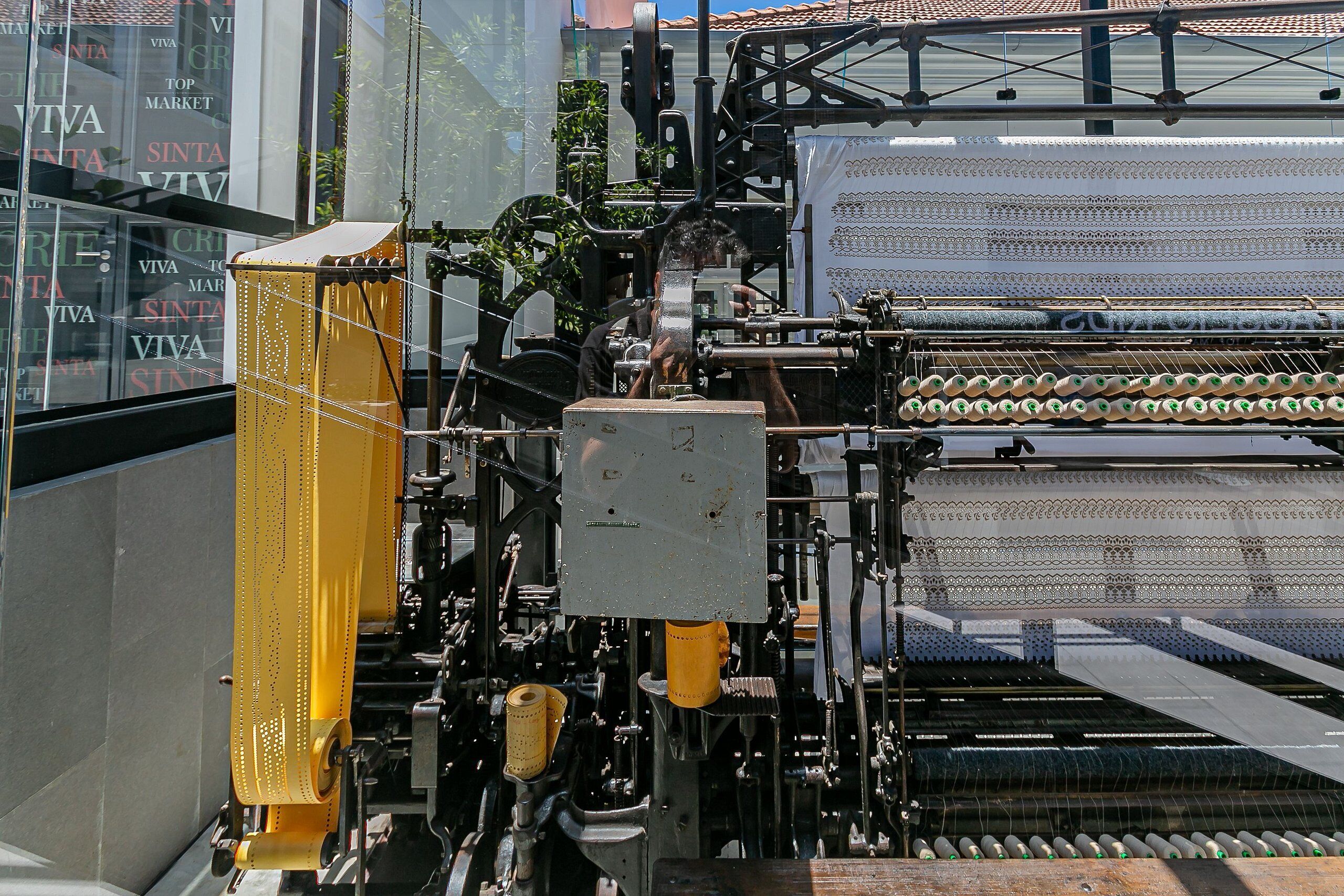 Máquina de fabricación textil con múltiples bobinas y componentes mecánicos.