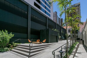 Un edificio moderno con una escalera, asientos exteriores y una palmera.