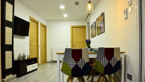 Un comedor con una mesa y sillas blancas, un armario blanco y negro, y una puerta de madera al fondo.