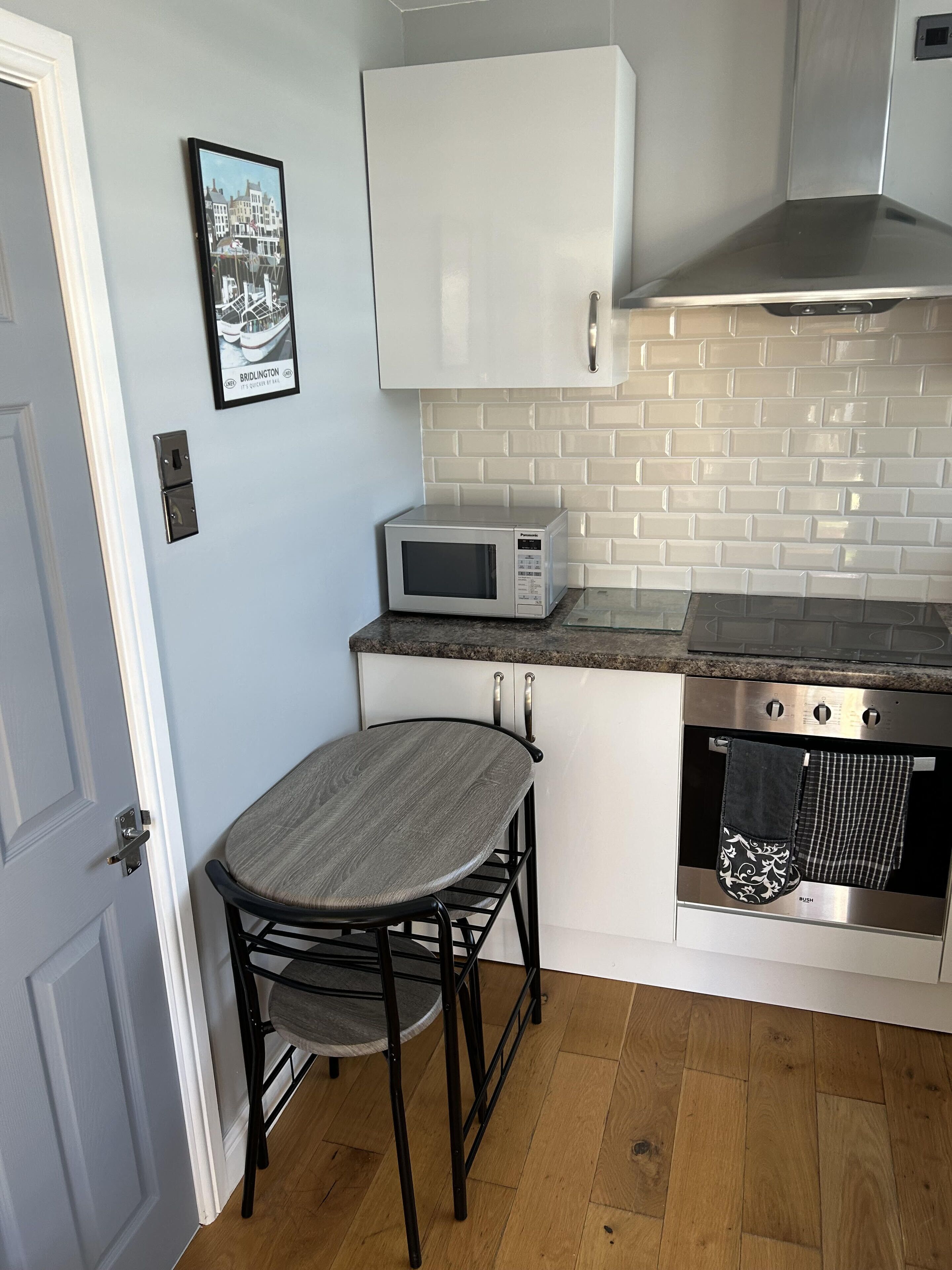 A compact kitchen with a microwave, oven, and a small dining table with two chairs.