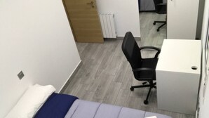 Un dormitorio con una cama, un escritorio y una silla.
