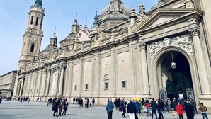 Un edificio histórico con una gran cúpula central y varias cúpulas más pequeñas, con detalles arquitectónicos intrincados y una destacada torre del reloj.