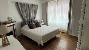 A bedroom with a bed, bedside tables, a desk, and a chair.
