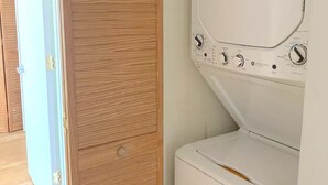 Une buanderie avec une porte en bois et un lave-linge blanc.