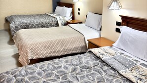 Habitación de hotel con dos camas, cabecera de madera, mesita de noche y lámpara colgante.
