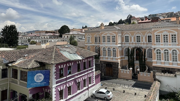 Un edificio histórico con tejado de tejas y un cartel grande.