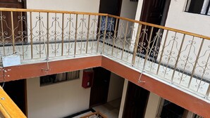 Un edificio residencial de varios niveles con una escalera central, balcones y barandilla de madera.
