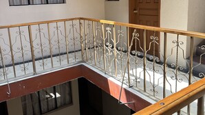 Un edificio residencial de varios niveles con un balcón que presenta barandilla de madera y balaustrada decorativa de metal.