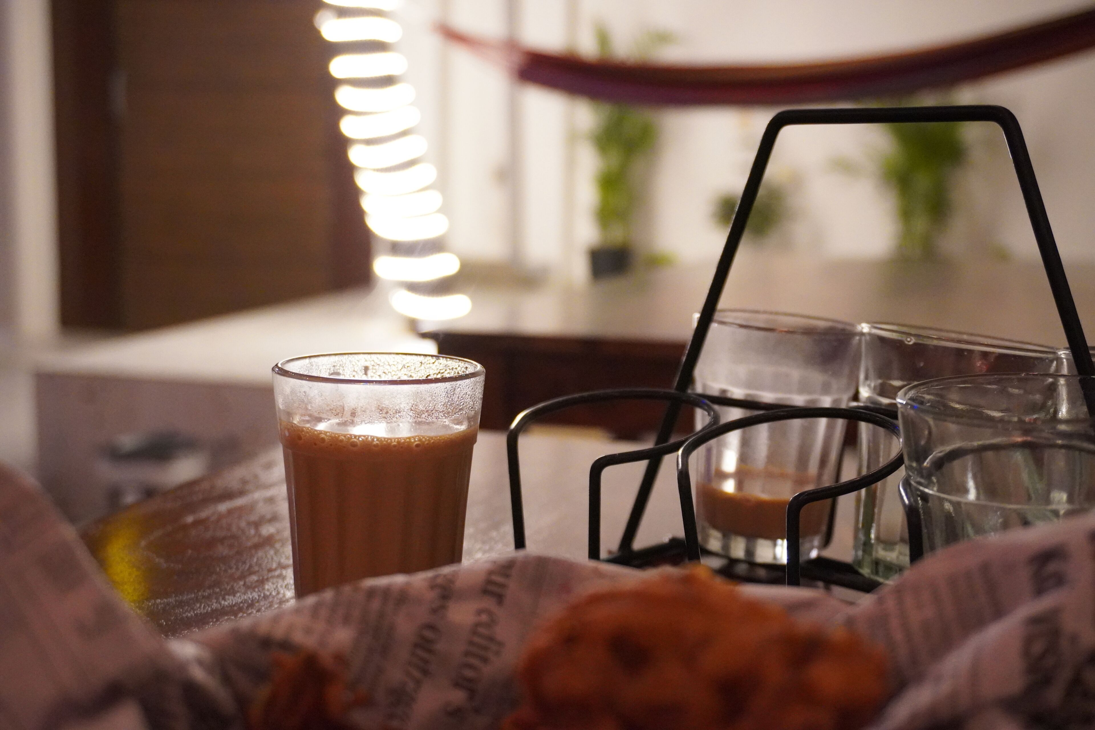 Une tasse de café sur un plateau, accompagnée d’une bougie et d’un verre d’eau.
