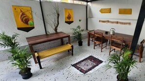 Un espacio interior acogedor con un banco de madera, una mesa de comedor con sillas y plantas en macetas.