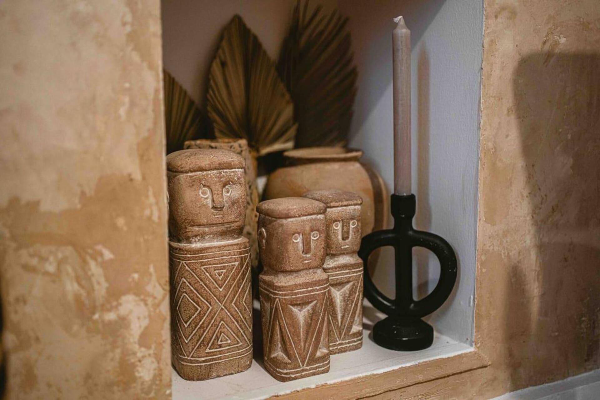 Una estantería con tres figuritas de cerámica y un candelabro.