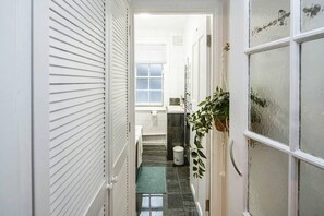 A narrow hallway with a tiled floor, a small window, and a plant on the right. - Central London, 5 Min 2 Angel Tube Station (London)