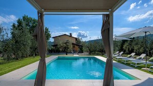 A pool with a pergola, lounge chairs, and a house in the background. - Villa Amore, a Romantic Hilltop Farmhouse in Lucca (Lucca)