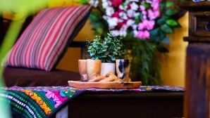 A cozy room with a wooden table, a colorful woven blanket, and a chair with a striped pillow.
