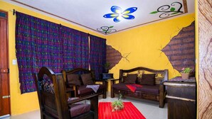 A room with two wooden sofas, a red rug, and a wall with a brick pattern.