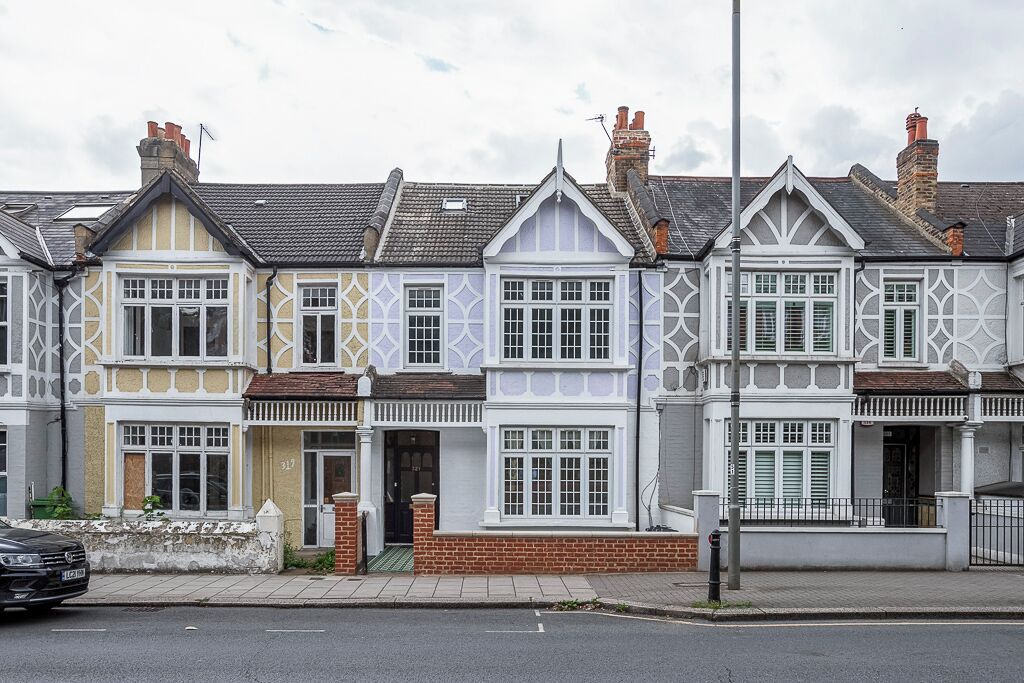 A row of terraced houses with distinct architectural styles, including white and pastel facades, and a brick entrance.