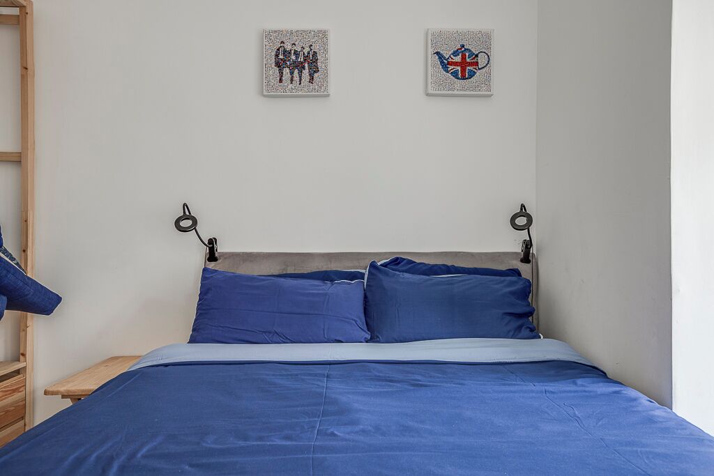 Une chambre à coucher avec un lit, des oreillers et deux œuvres d’art accrochées au mur.