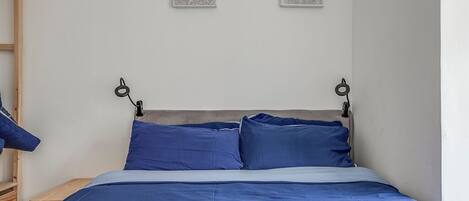 Une chambre à coucher avec un lit, des oreillers et deux œuvres d’art accrochées au mur.
