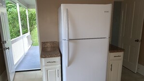 Una cocina con un refrigerador blanco, armarios blancos y una encimera de madera.