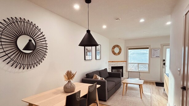 Een moderne woonkamer met een eethoek, een open haard en een grote spiegel aan de muur.