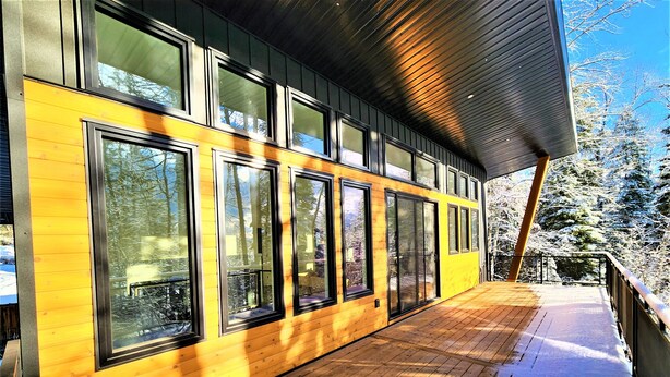 En modern byggnad med stora fönster och en träaltan.