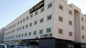 A multi-story building with a sign for "100 Evening Cafe" and a sign for "Mina." - Zahrat Alandalus Apartments (Riyadh)
