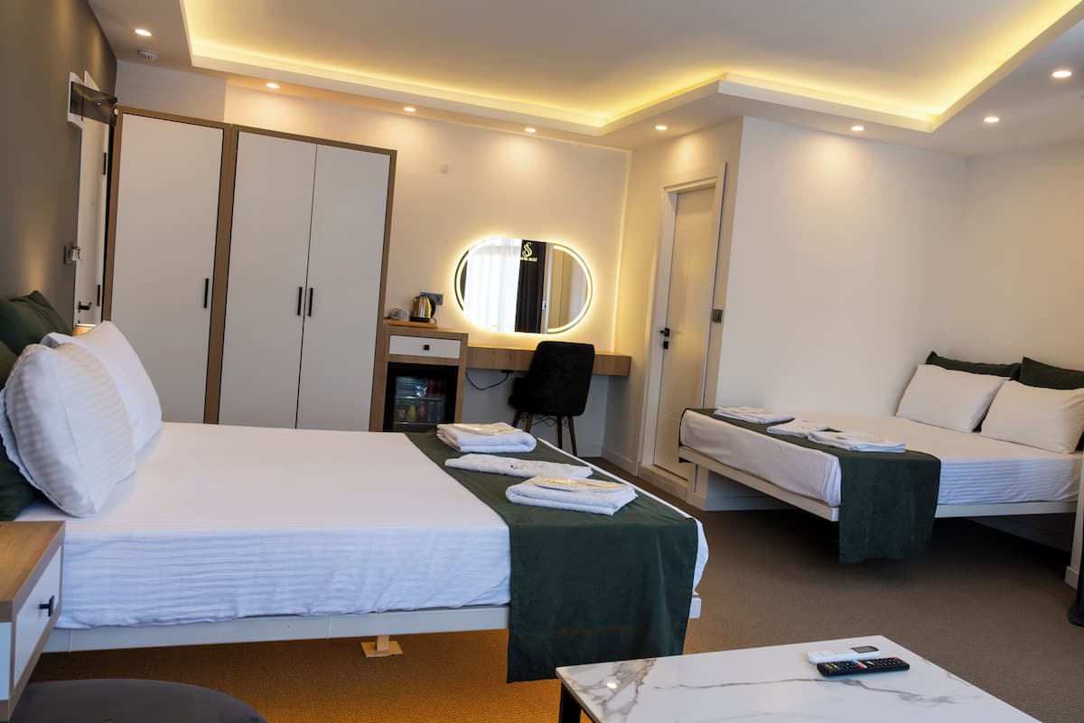 Una habitación de hotel con dos camas, un escritorio, una silla, un espejo y un armario.