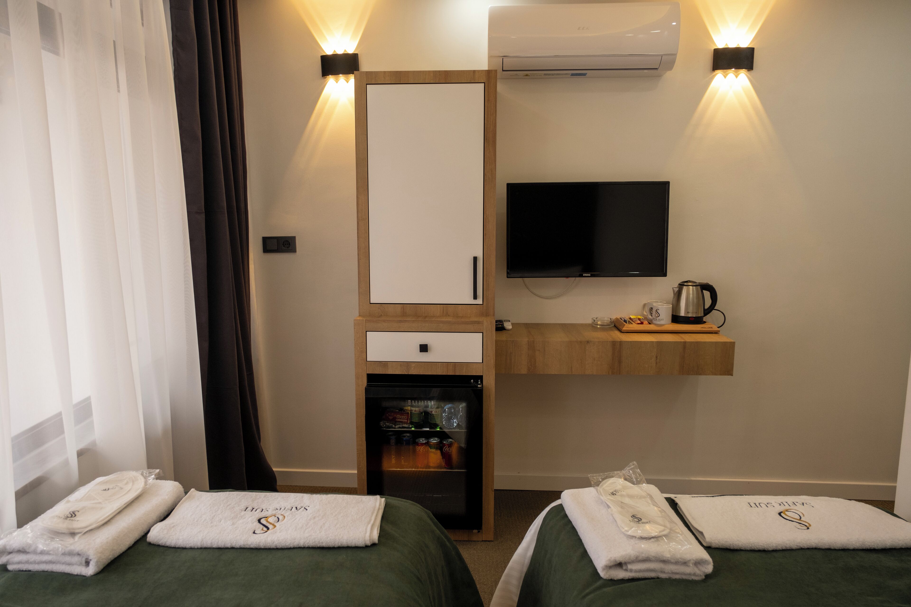 Une chambre d’hôtel avec deux lits, une télévision, un minibar et un miroir.