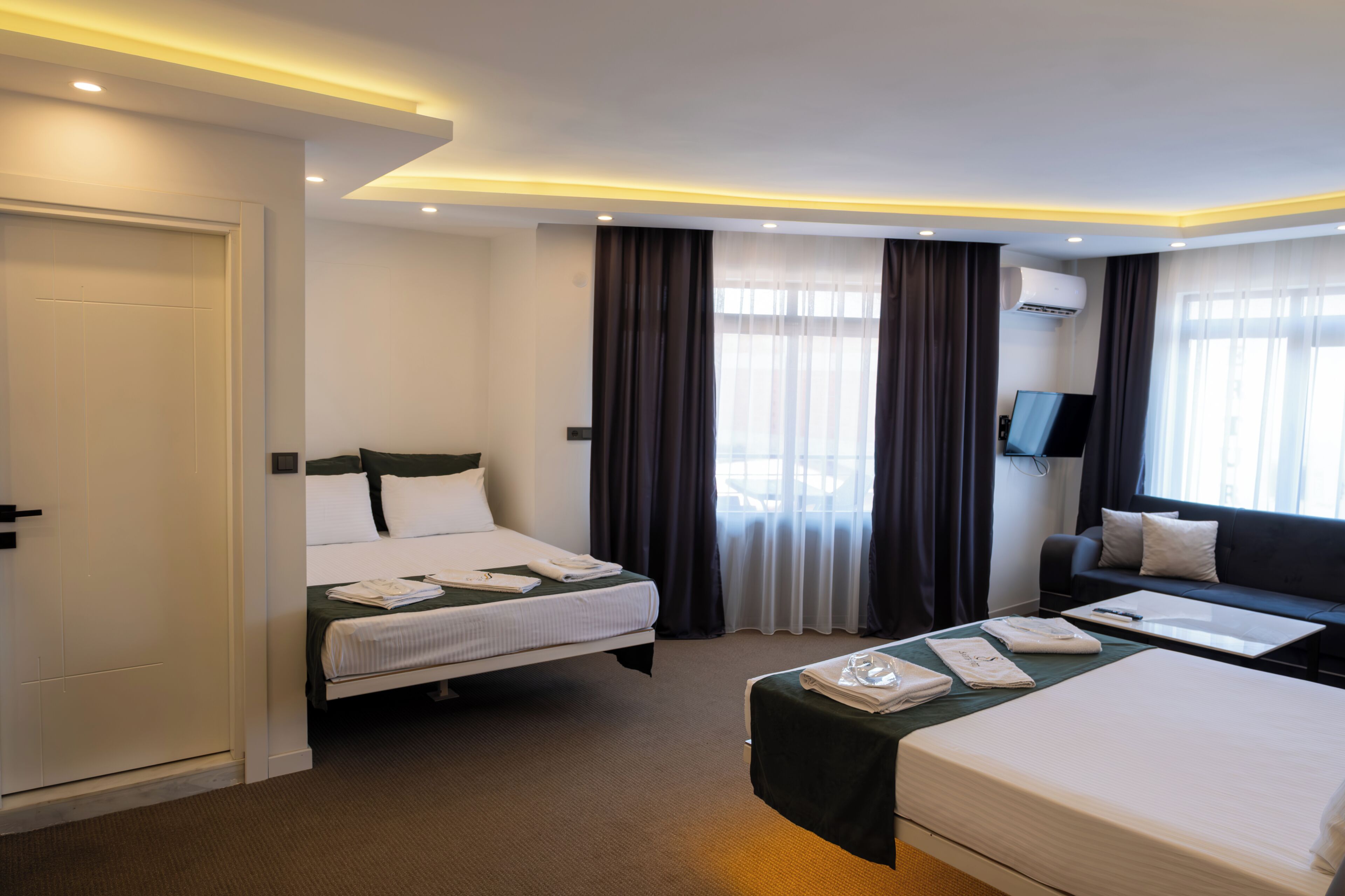 Una camera d'albergo con un letto, una poltrona letto, una TV a schermo piatto e una scrivania.