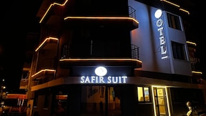 A building with a sign reading "SAFIR SUIT HOTEL" and a scooter parked in front.