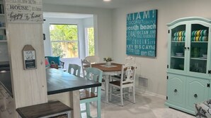 Un coin repas avec une table et des chaises, un meuble avec des portes en verre et un panneau accroché au mur.