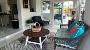 Un vaste espace de vie agrémenté d’un ventilateur de plafond, d’une table ronde avec un panier, d’un canapé avec des coussins colorés et d’un tapis à motifs.