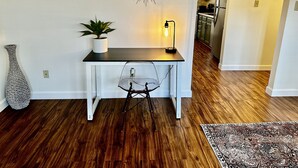 Un petit coin repas comprenant une table, une chaise, une plante en pot et une horloge murale.