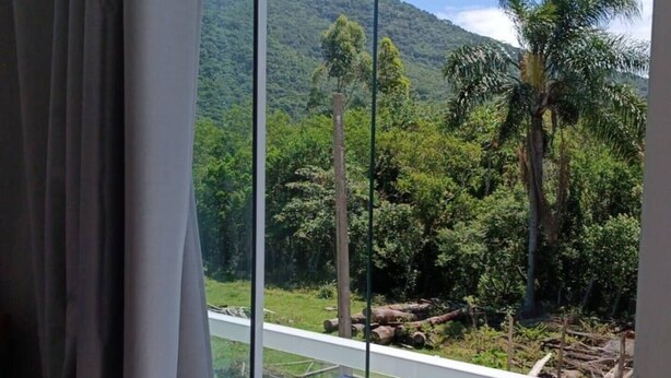 Una habitación con un amplio ventanal que da a un paisaje montañoso con vegetación y una zona pavimentada.