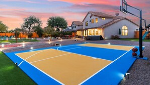 Una cancha de baloncesto al aire libre con una casa al fondo.