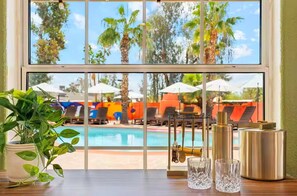 A view of a poolside area with lounge chairs and umbrellas, a potted plant, and a table with a bottle and glasses. - Heated Pool, Volleyball, Pickleball, Hot Tub! Oasis Resort (Scottsdale)