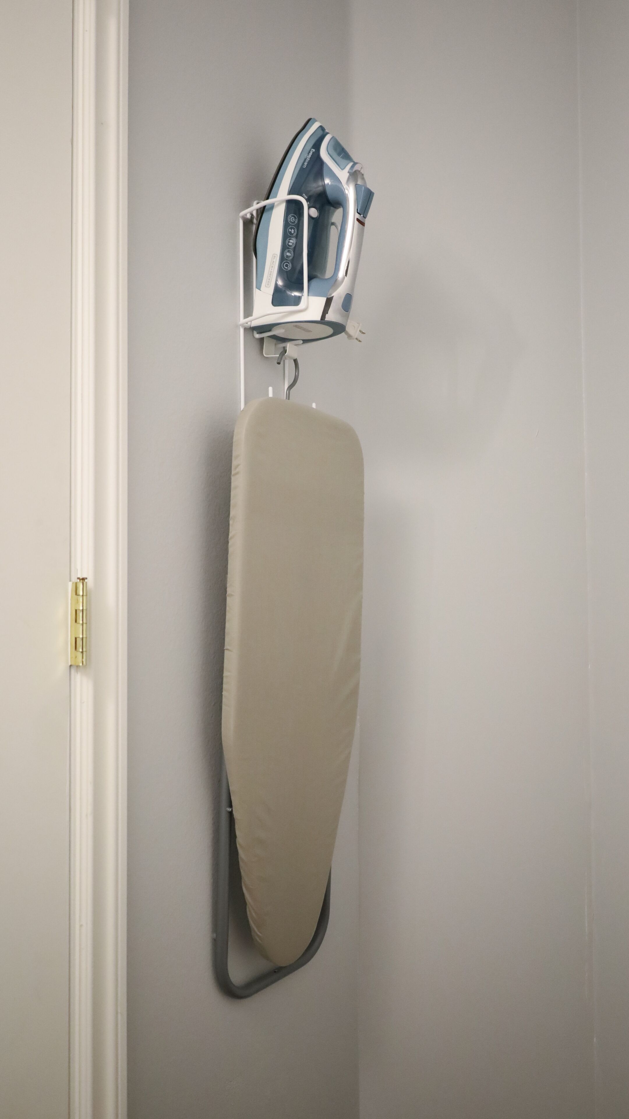 A wall-mounted ironing board with a protective cover.