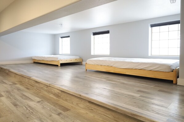 Une pièce avec deux lits en bois, un plafond en pente et de grandes fenêtres.